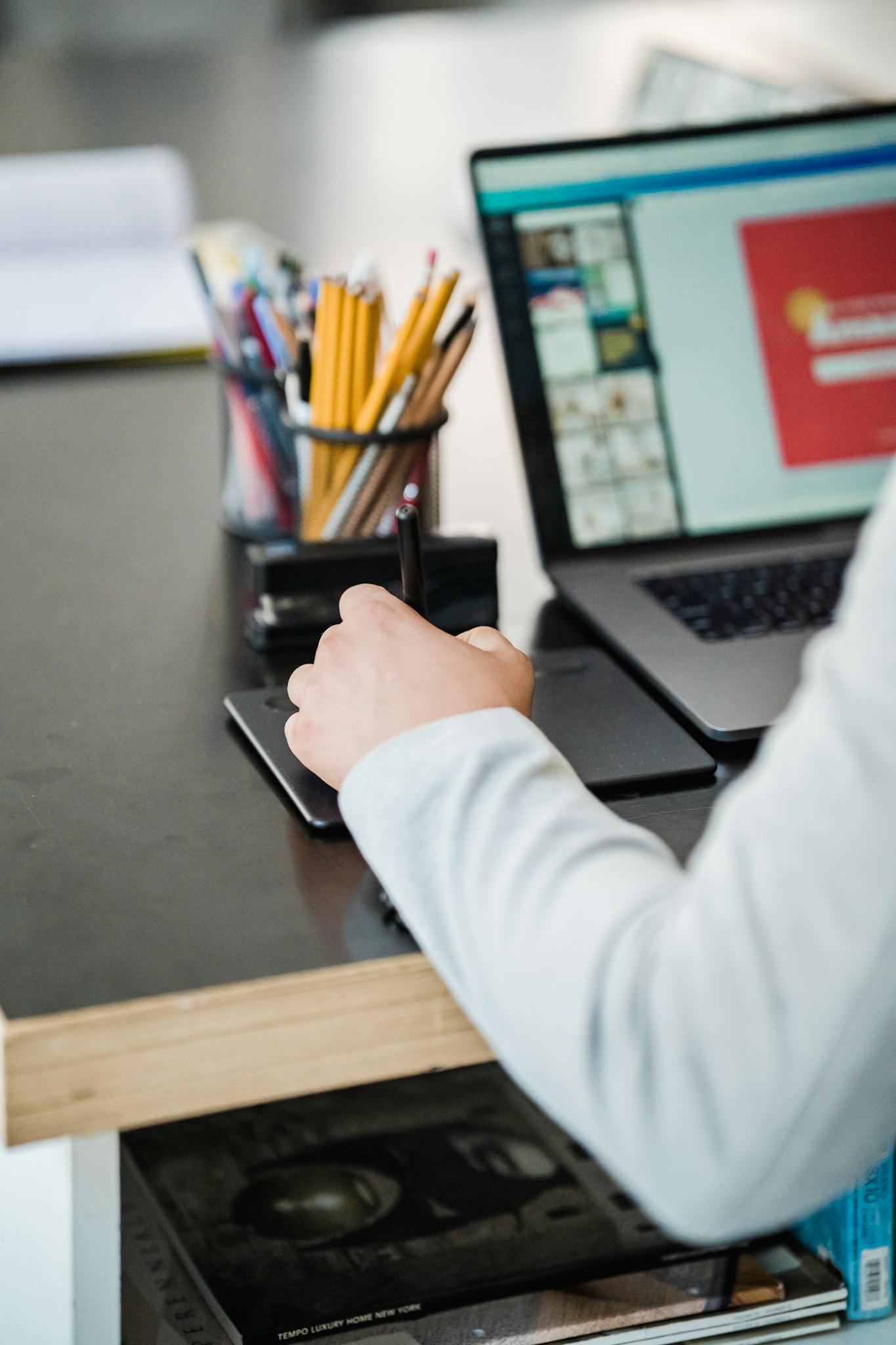 Close-up of a person using a digital tablet and laptop in a modern office setting.